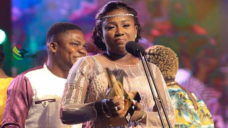 Diana Hamilton holding the VGMA Artiste of the Year trophy on stage