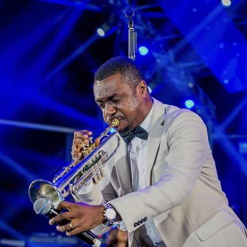 Nathaniel Bassey performing on stage with his trumpet